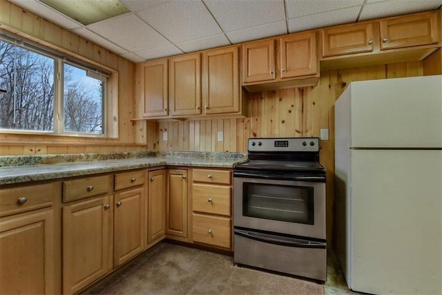 kitchen with wooden walls, stainless steel electric range oven, light countertops, carpet, and freestanding refrigerator