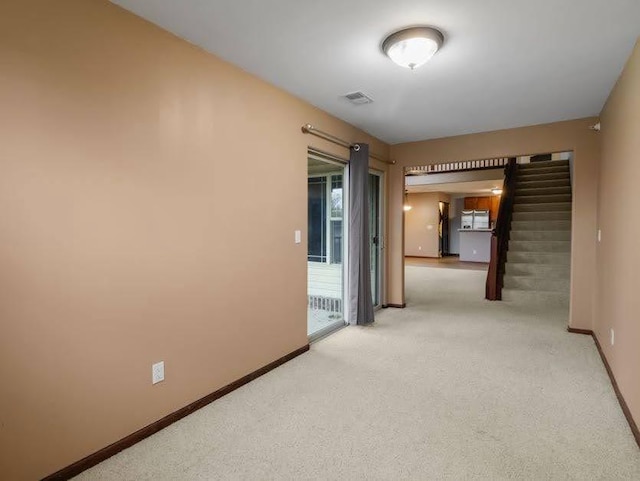 interior space featuring carpet flooring, baseboards, visible vents, and stairway