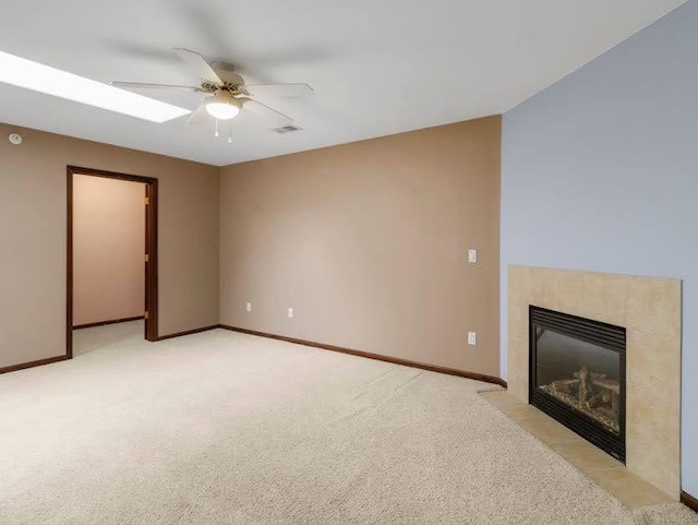 unfurnished living room with ceiling fan, visible vents, light colored carpet, a tile fireplace, and baseboards