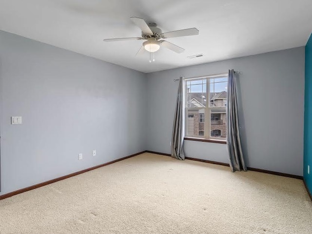 spare room featuring baseboards, visible vents, a ceiling fan, and light colored carpet
