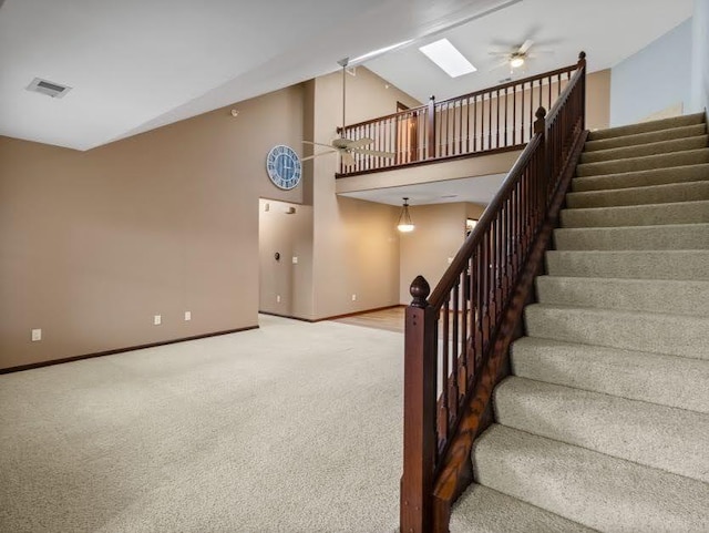 stairs with baseboards, carpet, a ceiling fan, and visible vents