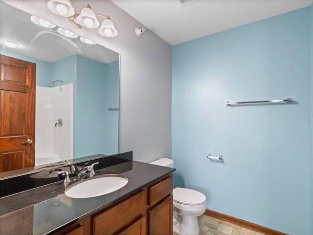 bathroom featuring toilet, baseboards, walk in shower, and vanity