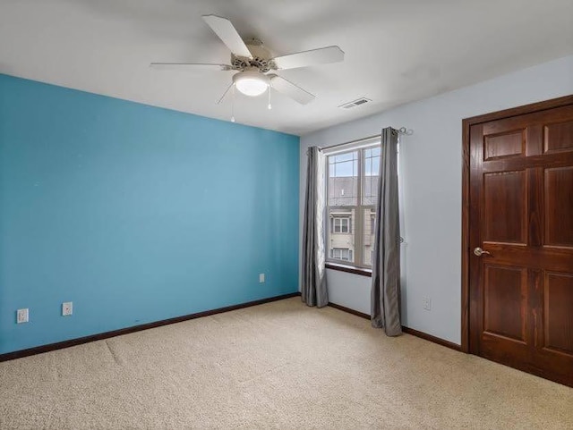 empty room featuring ceiling fan, visible vents, light carpet, and baseboards