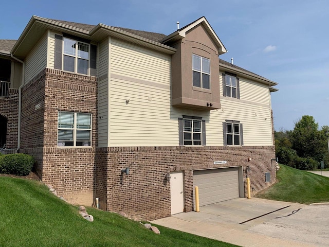 view of property exterior featuring an attached garage, a yard, driveway, and brick siding