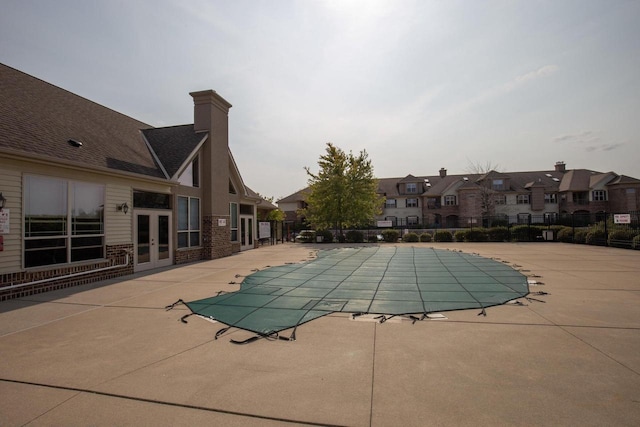 pool featuring a patio, fence, french doors, and a residential view