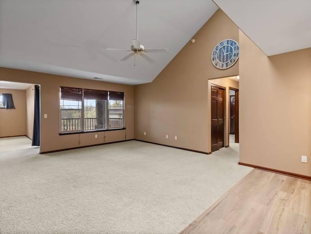 unfurnished living room featuring a ceiling fan, high vaulted ceiling, light colored carpet, and baseboards