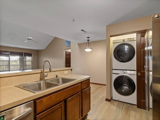 laundry area with stacked washer and dryer, laundry area, ceiling fan, a sink, and light wood finished floors
