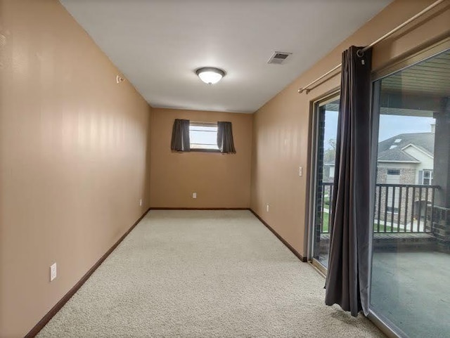 spare room featuring visible vents, baseboards, and light carpet