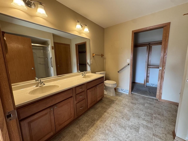 3027 S Bartells Dr, Beloit, WI 53511 - bathroom with double vanity, a shower stall, toilet, and baseboards
