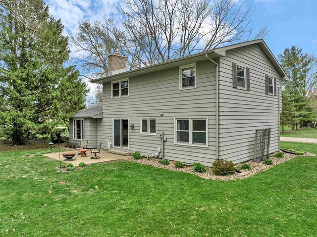 6643 Forest Park Dr, Deforest, WI 53532 - back of house featuring a lawn, a patio area, a chimney, and an outdoor fire pit