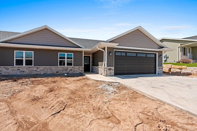 craftsman inspired home with an attached garage, driveway, and stone siding