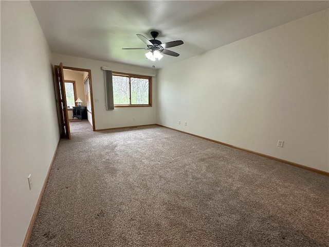 empty room featuring baseboards, a ceiling fan, and light colored carpet