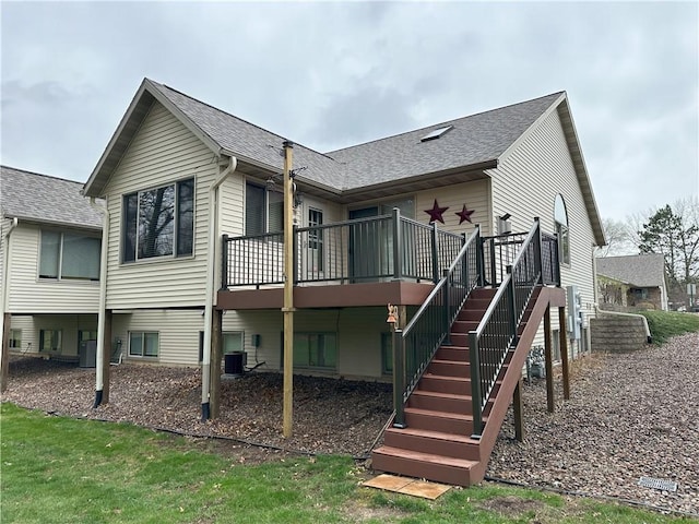 rear view of property featuring cooling unit, a wooden deck, and a shingled roof