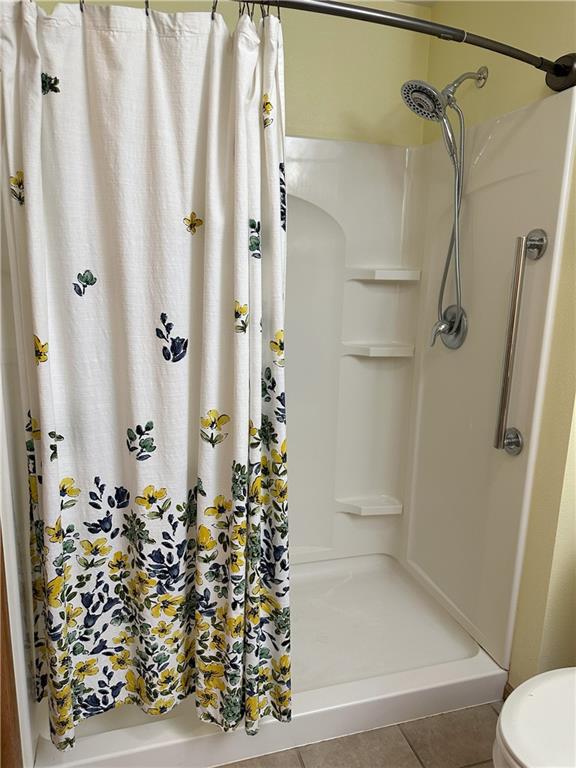 bathroom featuring toilet, a shower with shower curtain, and tile patterned flooring