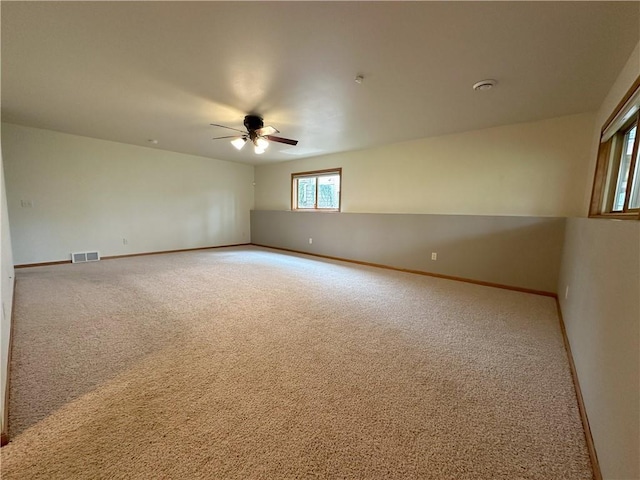 empty room with visible vents, carpet, ceiling fan, and baseboards