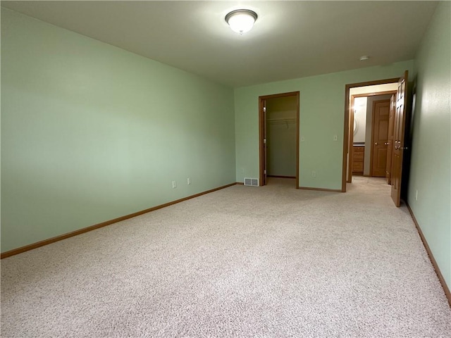 unfurnished bedroom with light colored carpet, visible vents, and a closet