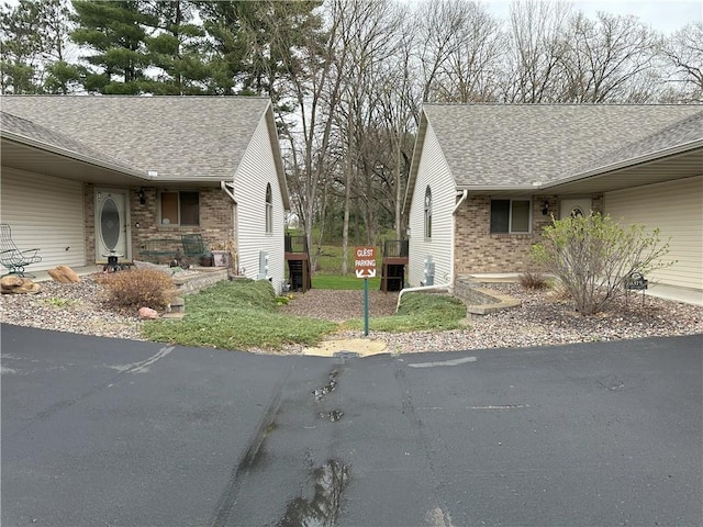 view of property exterior with brick siding and a shingled roof