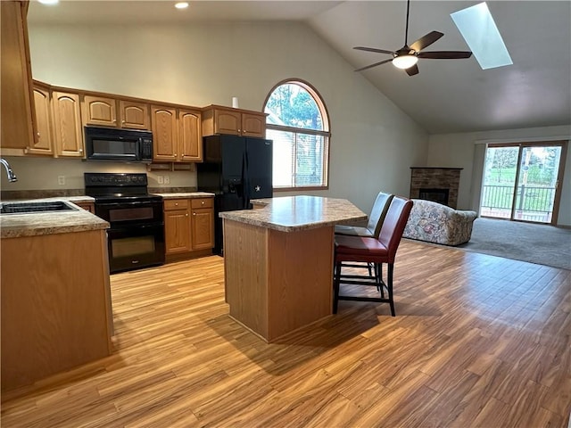 kitchen with a fireplace, open floor plan, high vaulted ceiling, a sink, and black appliances