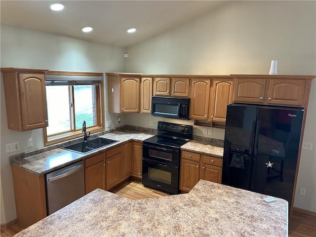 kitchen with lofted ceiling, light wood-style floors, brown cabinets, a sink, and black appliances