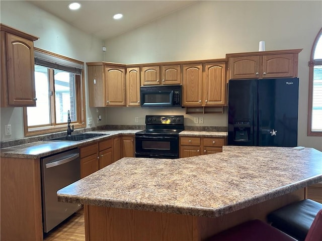 kitchen with a kitchen island, a kitchen breakfast bar, recessed lighting, a sink, and black appliances