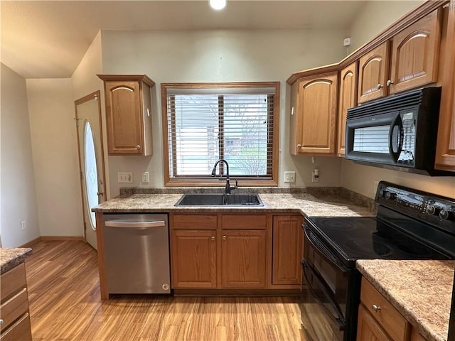 kitchen with a sink, light wood finished floors, and black appliances