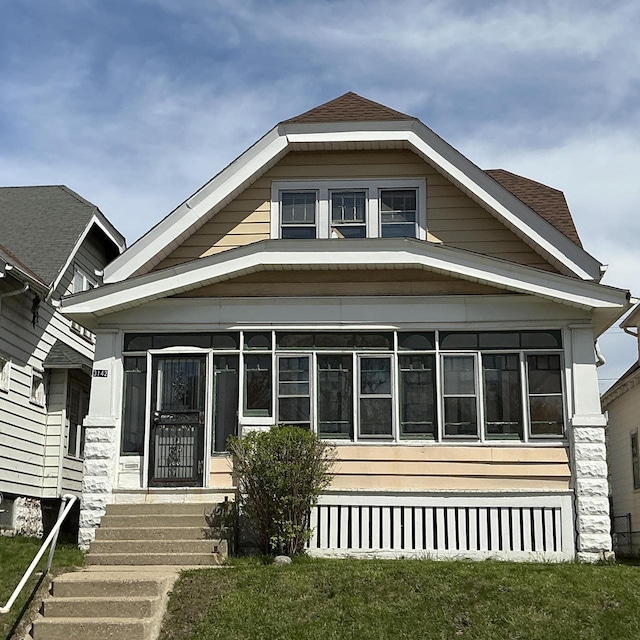 bungalow-style home featuring a sunroom and roof with shingles