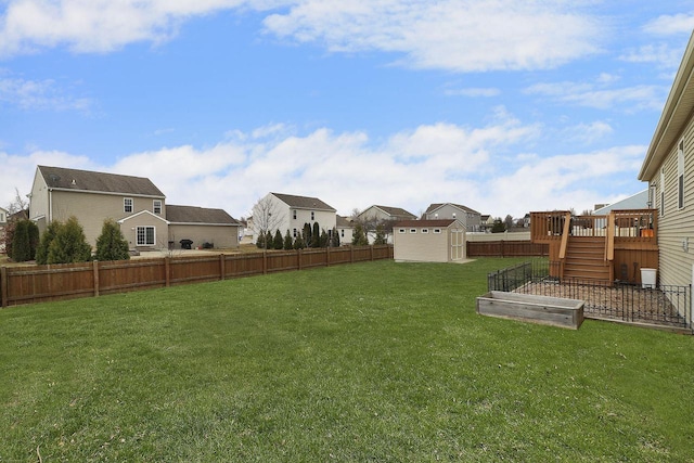 view of yard featuring a storage unit, a fenced backyard, and a residential view