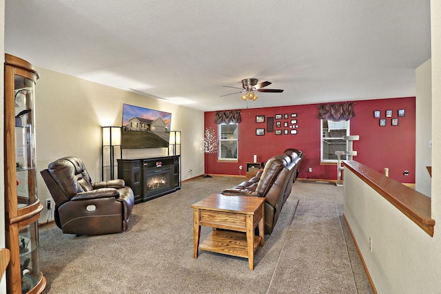 living room with carpet floors, ceiling fan, a glass covered fireplace, and baseboards