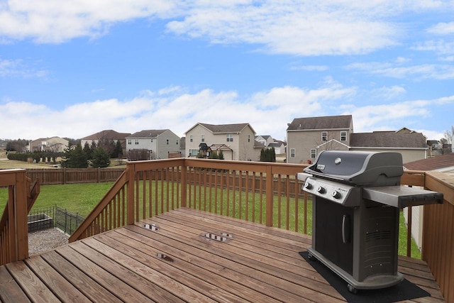wooden terrace with a residential view, a fenced backyard, a lawn, and grilling area
