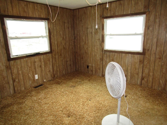 spare room featuring wooden walls, visible vents, and carpet floors