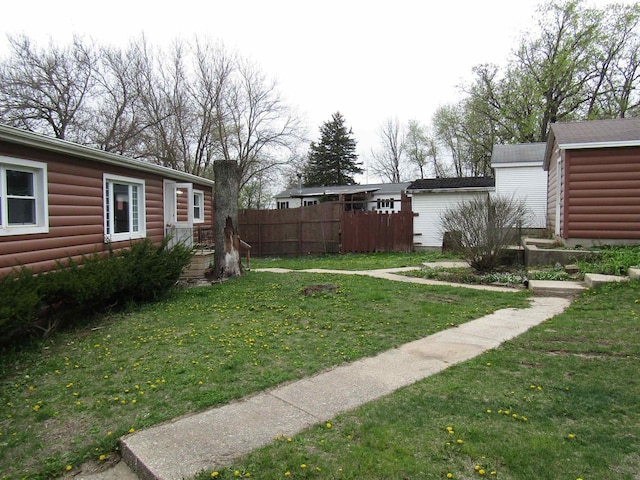 view of yard with an outdoor structure, fence, and a storage unit