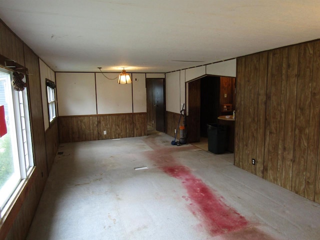 unfurnished living room featuring unfinished concrete floors and wooden walls