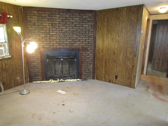 unfurnished living room with carpet flooring, wood walls, and a brick fireplace