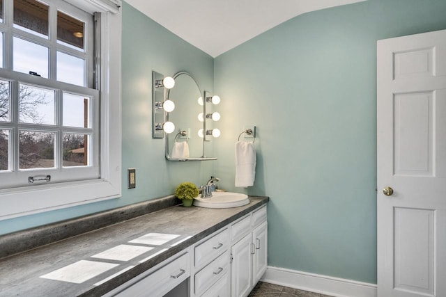 bathroom with vaulted ceiling, vanity, and baseboards