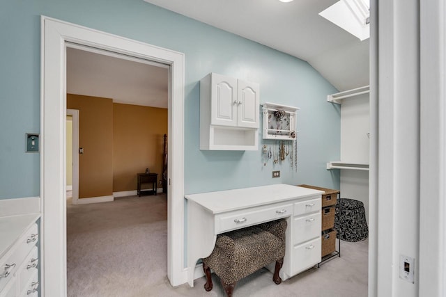 home office featuring vaulted ceiling with skylight, baseboards, and light colored carpet