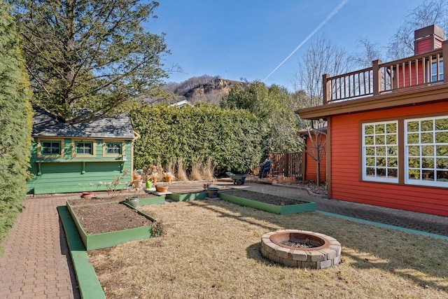 view of yard featuring an outdoor fire pit, a vegetable garden, a mountain view, and a balcony