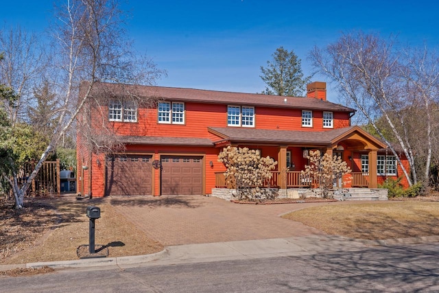 view of front of house with a chimney, driveway, covered porch, and a garage