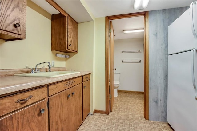 E5081 865th St, Boyceville, WI 54725 - interior space featuring a sink, brown cabinetry, freestanding refrigerator, light countertops, and baseboards