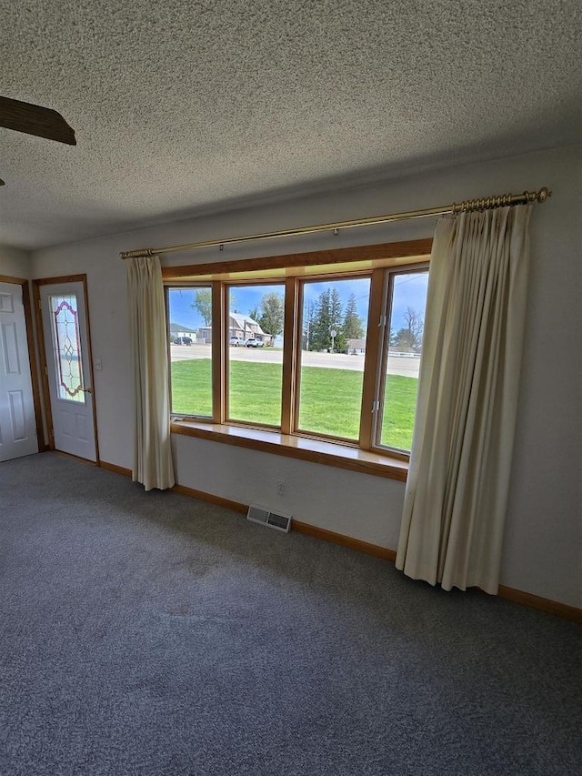 unfurnished room with a textured ceiling, baseboards, visible vents, and carpet floors