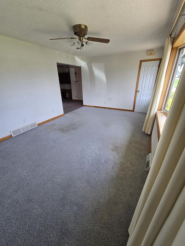 spare room featuring carpet, a textured ceiling, visible vents, baseboards, and ceiling fan