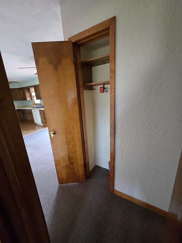 hallway with light carpet and a textured wall
