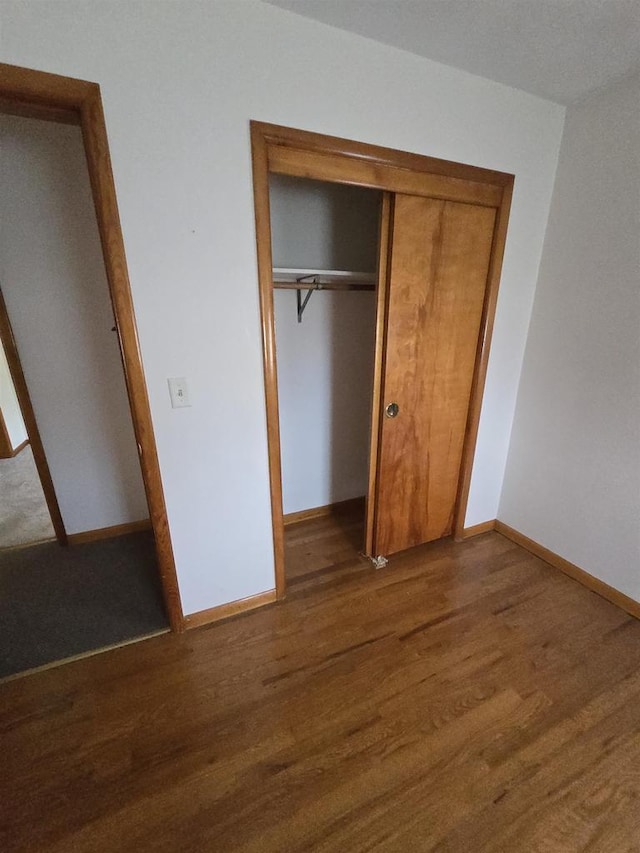 unfurnished bedroom featuring baseboards, a closet, and wood finished floors