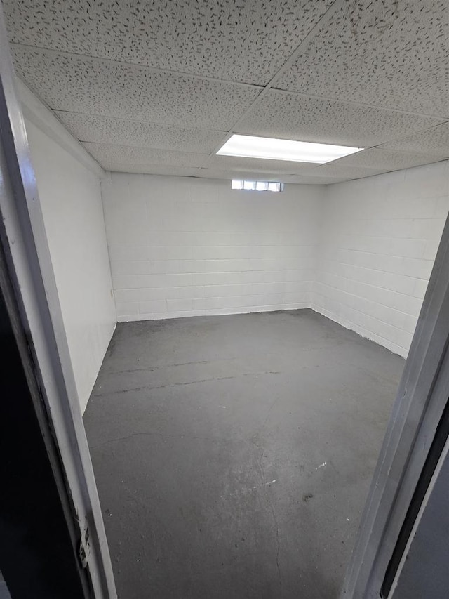finished below grade area with a drop ceiling and concrete block wall