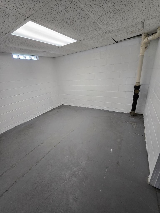 basement with a drop ceiling and concrete block wall