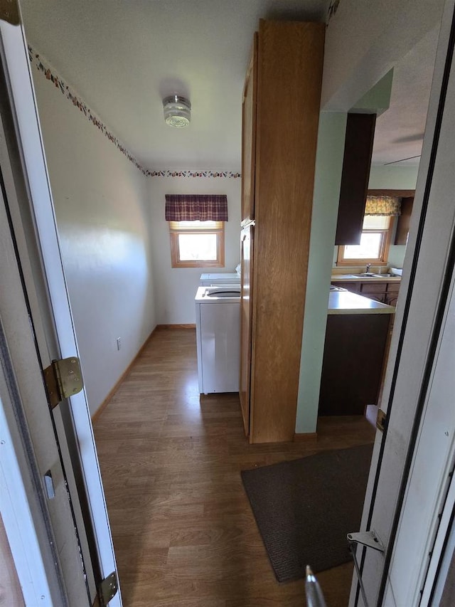 laundry area with independent washer and dryer, laundry area, a sink, and wood finished floors