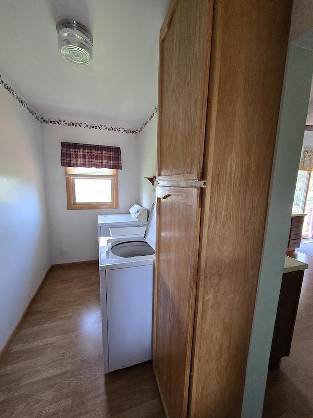clothes washing area with laundry area, plenty of natural light, dark wood-style flooring, and washing machine and dryer