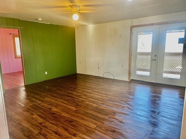 spare room featuring wooden walls, french doors, ceiling fan, and wood finished floors