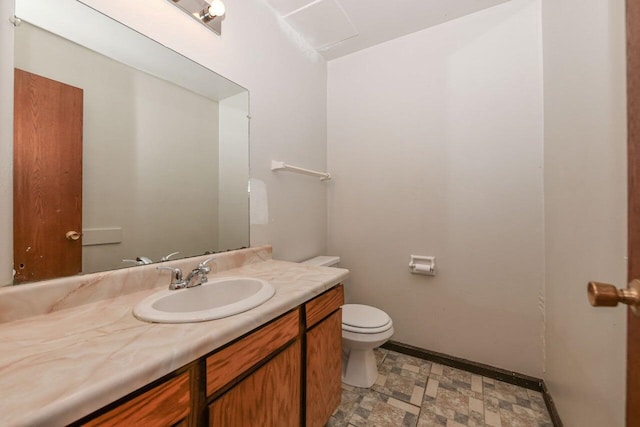 half bath with toilet, baseboards, and vanity