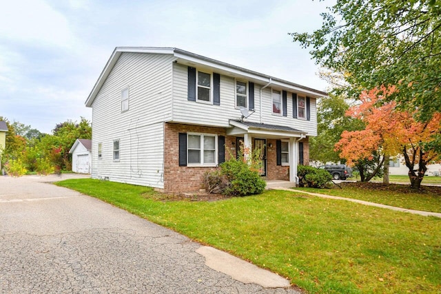 view of front of house featuring an outdoor structure, a detached garage, a front lawn, and brick siding