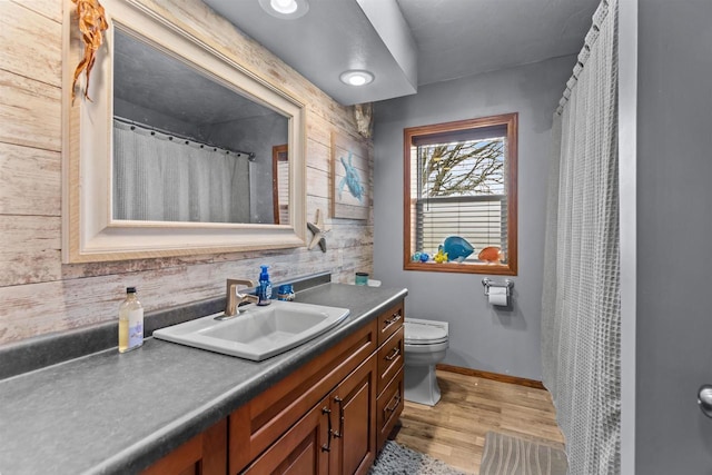bathroom featuring toilet, baseboards, vanity, and wood finished floors